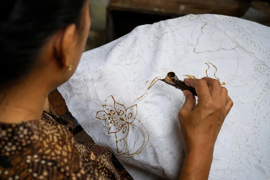 Een deelnemer brengt vloeibare malam aan op wit mori-katoen tijdens een batikles in Laweyan.