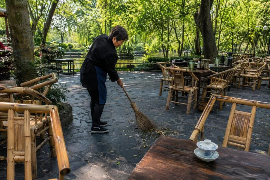 Staff sweep between bamboo chairs and low tables at Heming Teahouse in People’s Park.