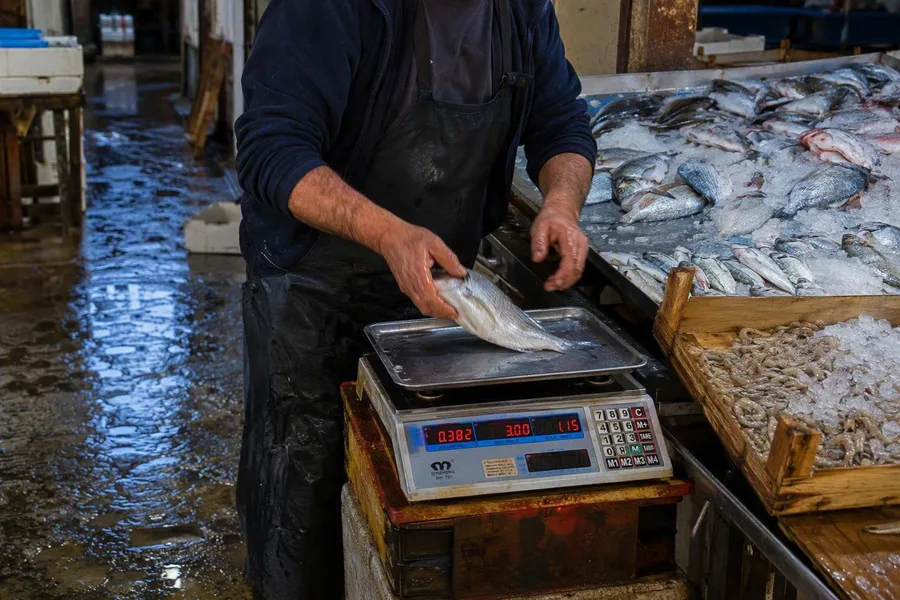 Een verkoper weegt vis van het ijs op de vismarkt van Batumi aan Baku Street 27.