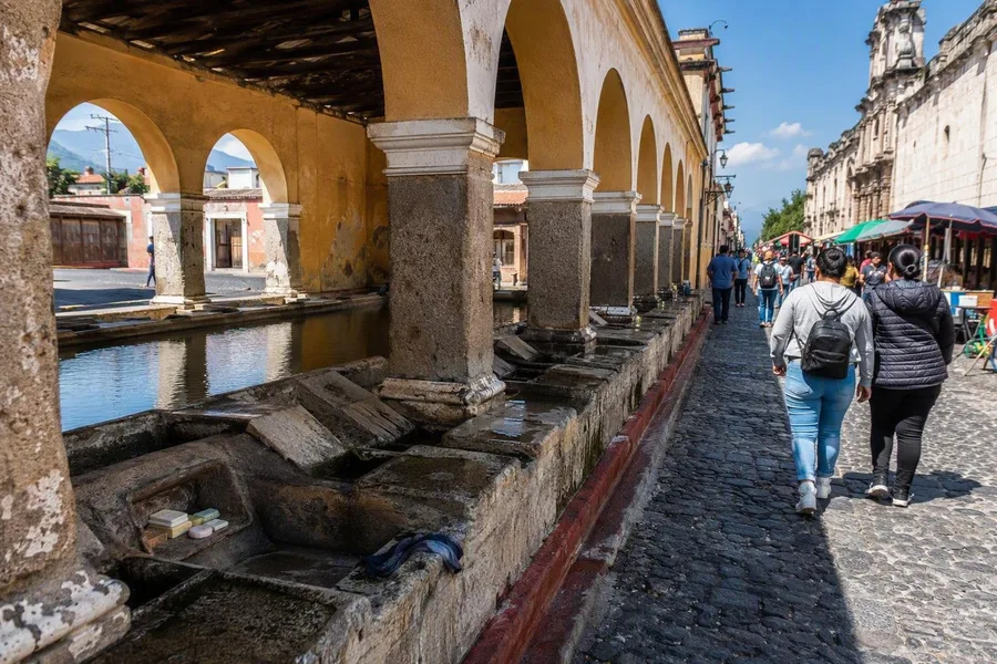 Pedestrians pass Tanque La Unión’s stone washing stations beside Plaza La Unión.