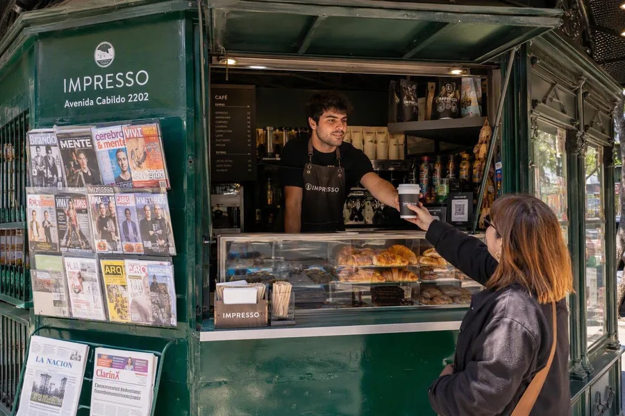 Een barista serveert koffie en laminados vanuit de kiosk van Impresso aan Avenida Cabildo.