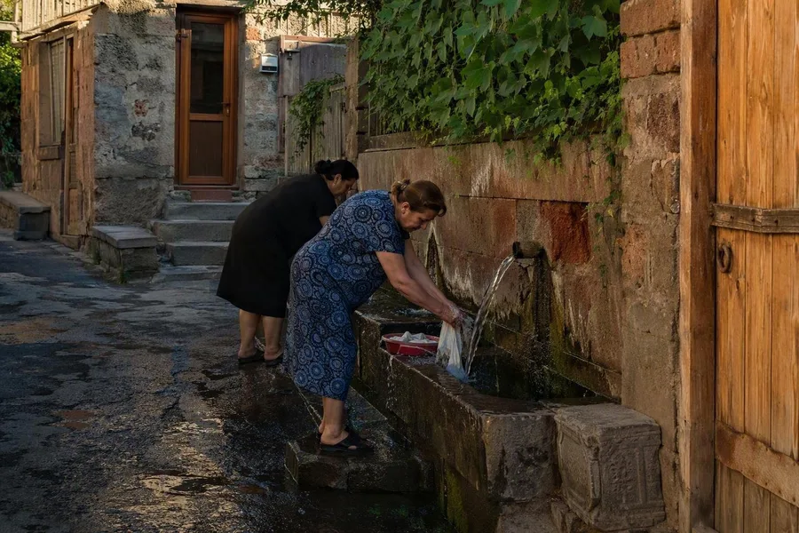 Residents wash at a communal spring beside stone seats in Kond’s narrow lanes.