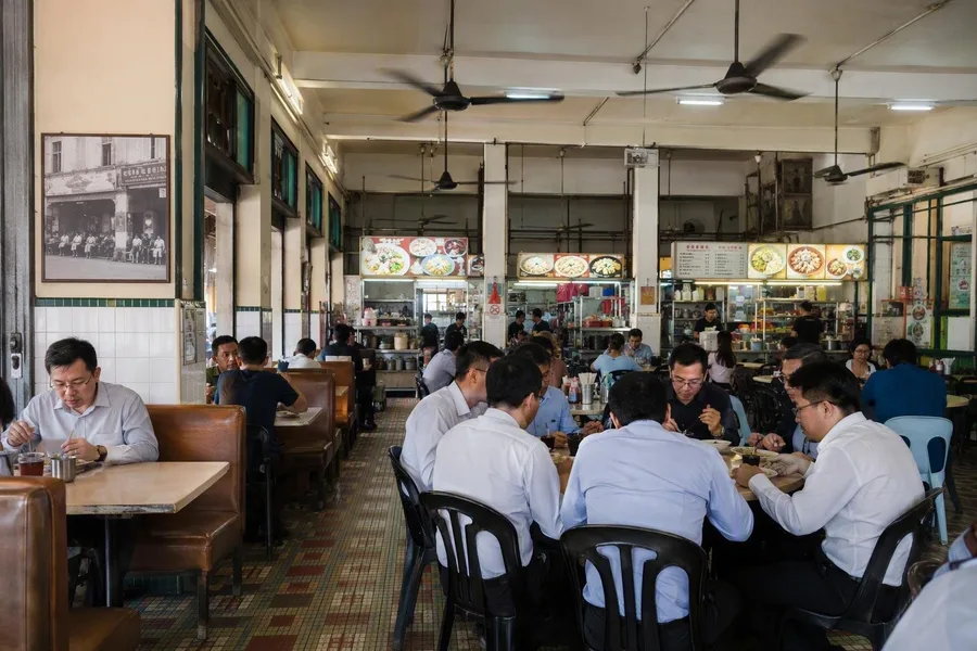 Kantoormedewerkers lunchen tussen de eetstalletjes bij Kek Seng aan Jalan Penang.