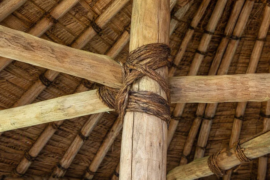Bouwers vlechten kokosvezelkoord rond het houten geraamte van een fale tele op Upolu.