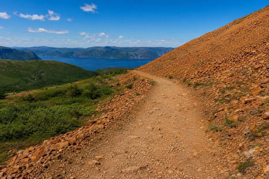 De gemarkeerde oude weg volgt roestoranje Tablelands-gesteente boven Bonne Bay.