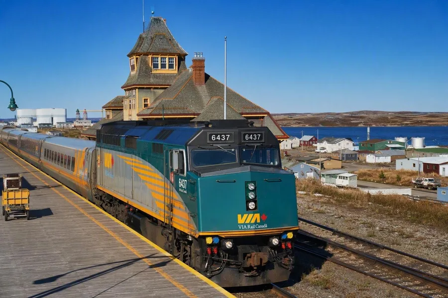 Een VIA Rail-trein arriveert bij het historische station van Churchill naast de lage kustplaats.