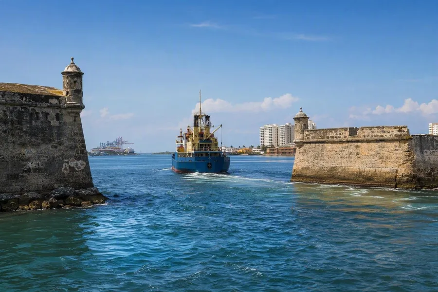 Een vaartuig vaart de beschutte baai van Cartagena binnen door ooit bewaakte doorgangen.