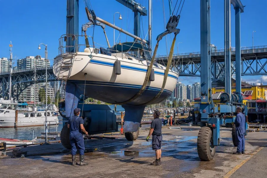 Werfmedewerkers hijsen een zeilboot uit False Creek voor reparatie op Granville Island.