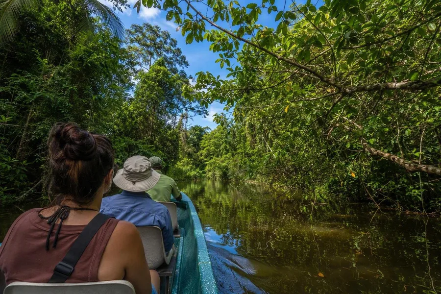 Passagiers varen per boot door een smal kanaal in Nationaal Park Tortuguero.