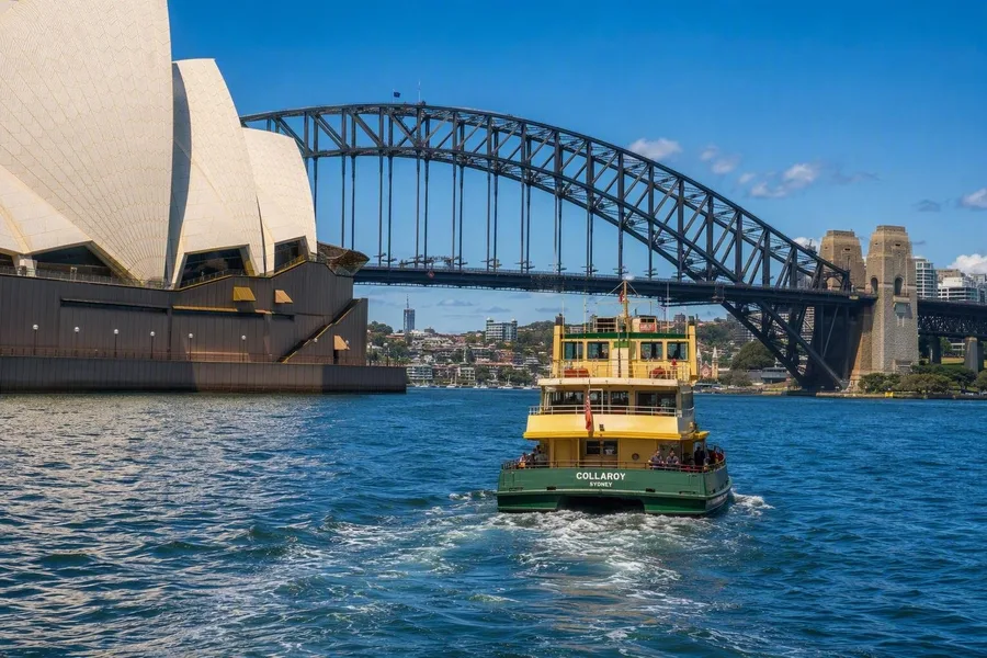 Een ferry vertrekt vanaf Circular Quay tussen het Opera House en de Harbour Bridge in Sydney.