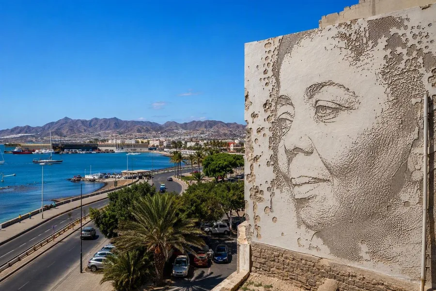 Het uit de wand geboorde portret van Cesária Évora rijst boven Avenida Marginal in Mindelo op.