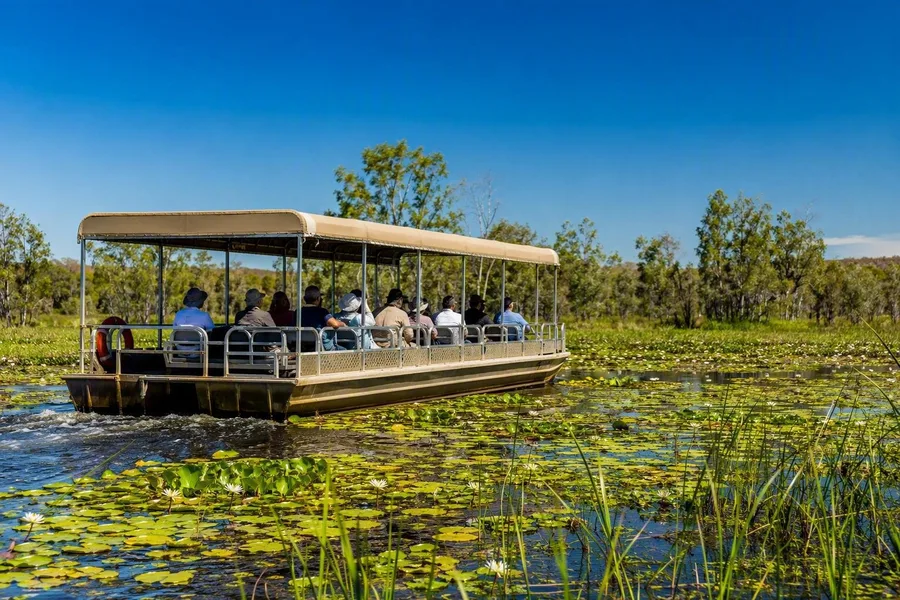 Een boot van Yellow Water Cruise vaart met passagiers over de vloedvlakte van Kakadu.