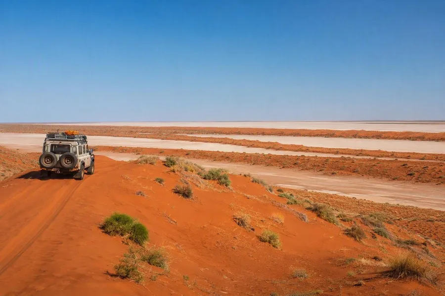 Een hoge 4WD rijdt over een rode zandrug in de Simpson Desert in Australië.