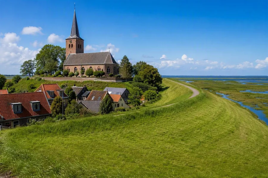 De Mariakerk van Wierum staat op de resterende terp naast de zeedijk en de Waddenzee.
