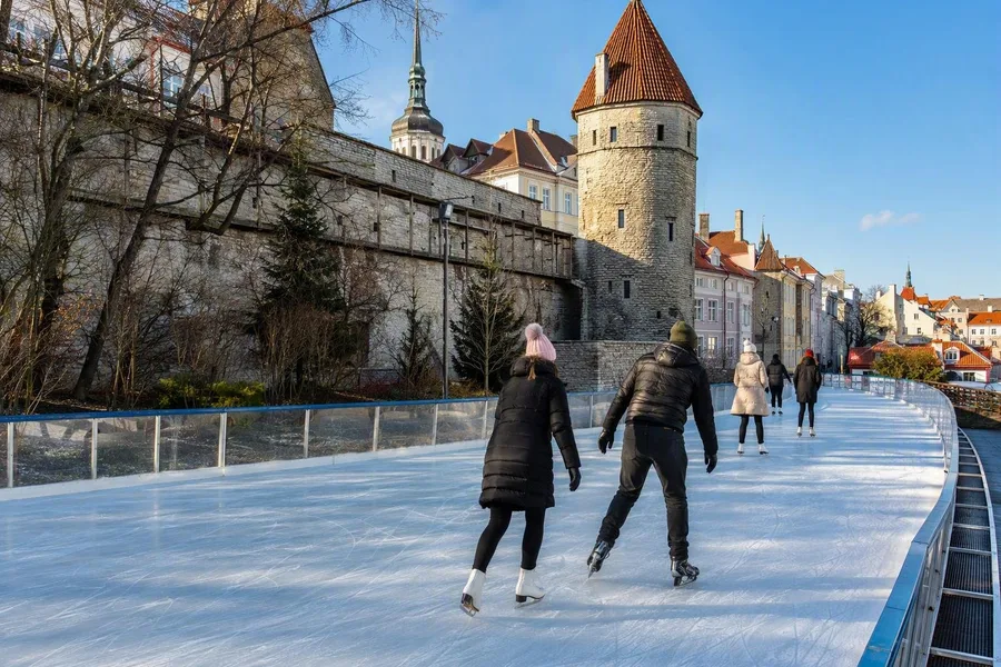 Schaatsers rijden rond op de buitenijsbaan in Harju Street tussen middeleeuwse gebouwen in Tallinn.