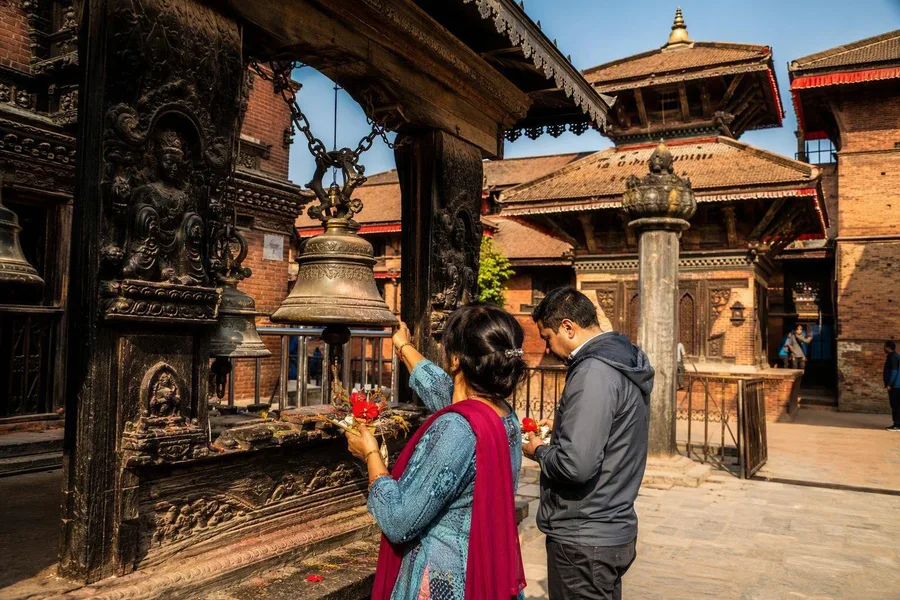 Gelovigen brengen offers en luiden bellen tussen de tempels op Kathmandu Durbar Square.