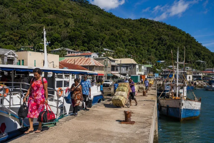 Passagiers en vracht komen aan bij Levuka Wharf, naast vissersschepen en de betonnen pier.