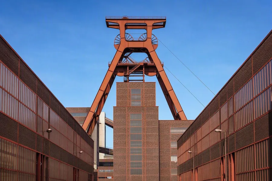 De dubbele schachttoren van Zollverein rijst boven rode bakstenen werkplaatsen in Essen.
