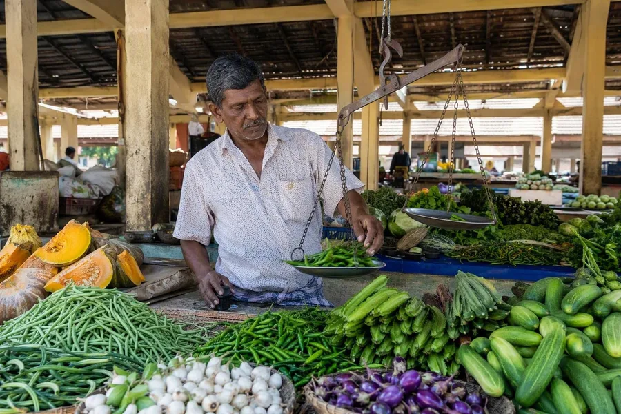 Een handelaar weegt groenten onder de open paviljoens van de gemeentelijke markt van Jaffna.