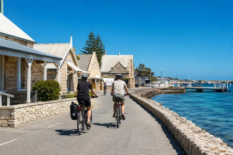 Fietsers met helm vertrekken van Main Jetty langs de kalkstenen gebouwen en zeewering van Thomson Bay.