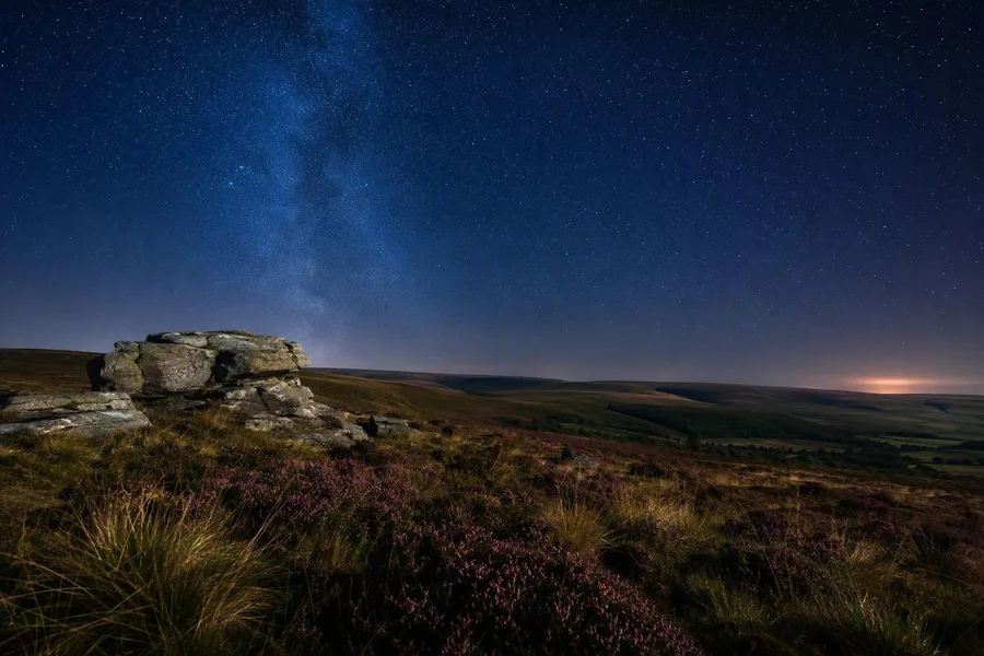 Open heide op Exmoor ligt onder een sterrenhemel boven de ruggen.