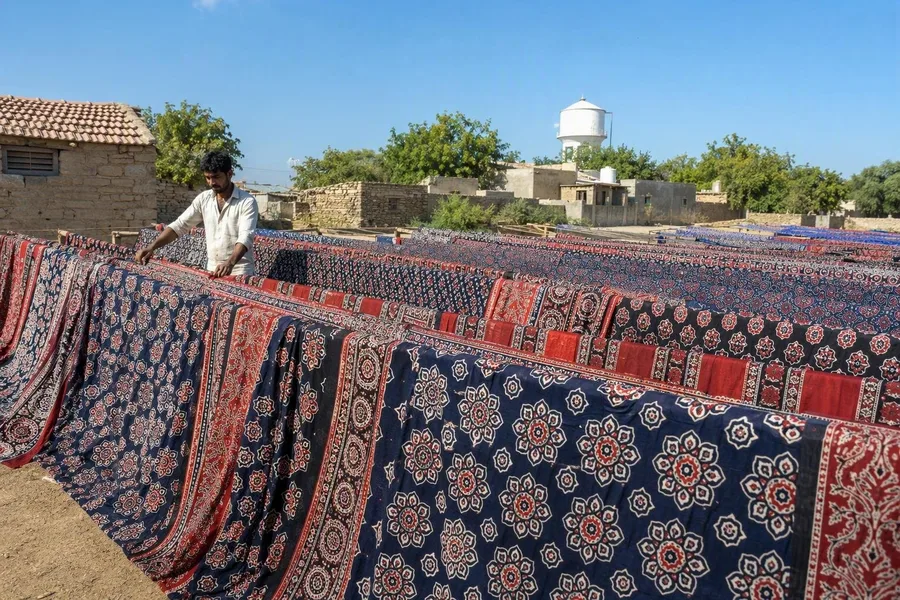 Ajrakh-makers spreiden pas gewassen katoen met patronen buiten in Ajrakhpur te drogen.