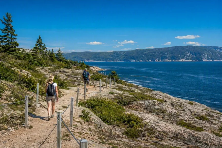 Bezoekers volgen het rotsachtige pad bij Pointe-de-l’Islet, met zicht op de Saguenay en Saint Lawrence.