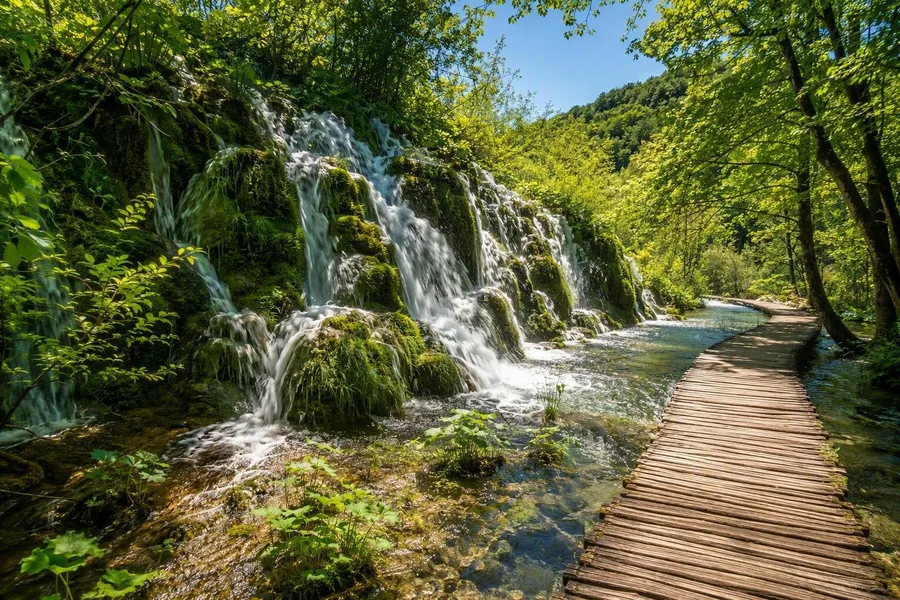 Een houten pad volgt cascades over tufdrempels in de Plitvicemeren.
