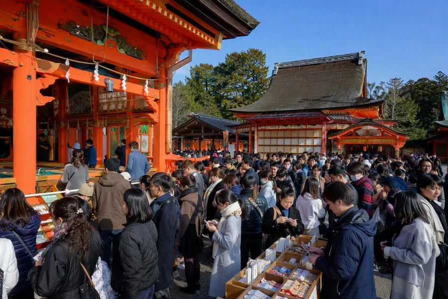 Bezoekers bidden en trekken fortune slips bij een schrijn in Kyoto tijdens hatsumōde.