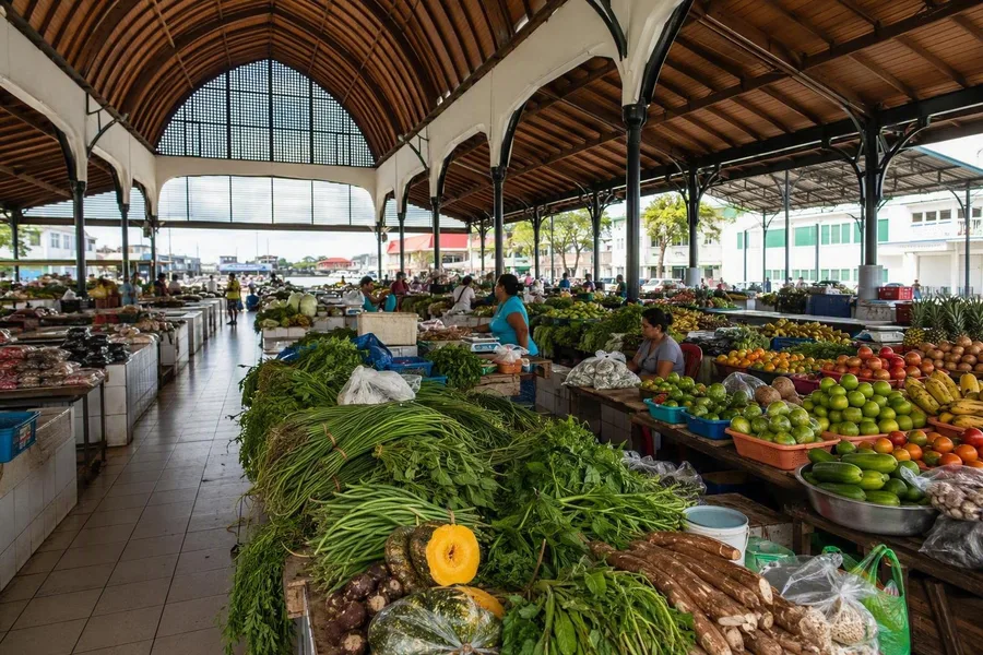 Groente- en fruitkramen vullen de begane grond onder het gebogen houten dak van de Centrale Markt in Paramaribo.