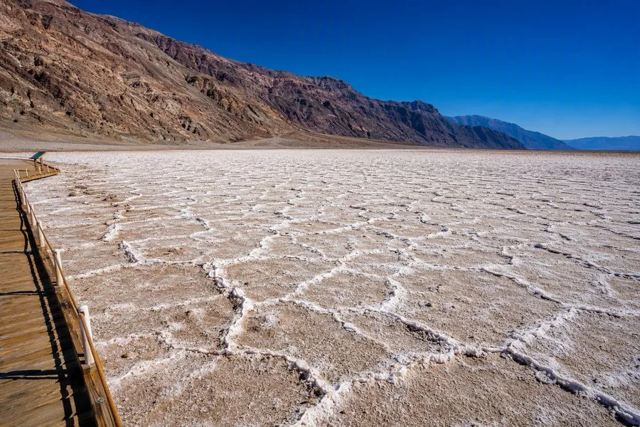 Witte zoutpolygonen bedekken Badwater Basin onder de steile bergen van Death Valley.