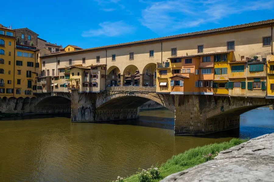 De uitstekende winkels en de gesloten Vasari-corridor van Ponte Vecchio overspannen de Arno in Florence.