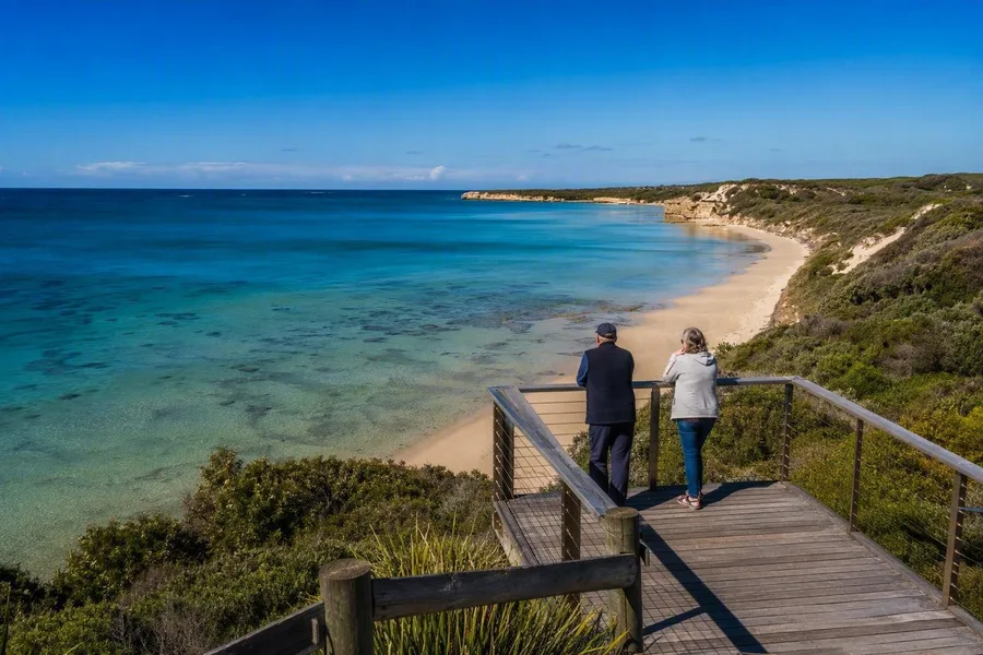 Bezoekers speuren vanaf het kijkplatform boven Logans Beach in Warrnambool de rustige ondiepten af.