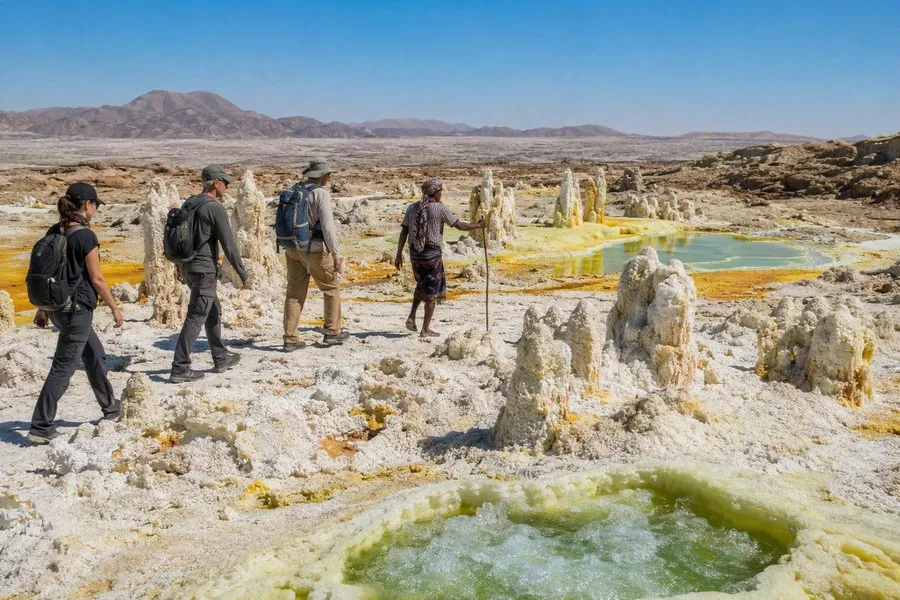 Bezoekers volgen een Afar-gids over Dallols broze zoutkorst langs mineraalpekelpoelen.